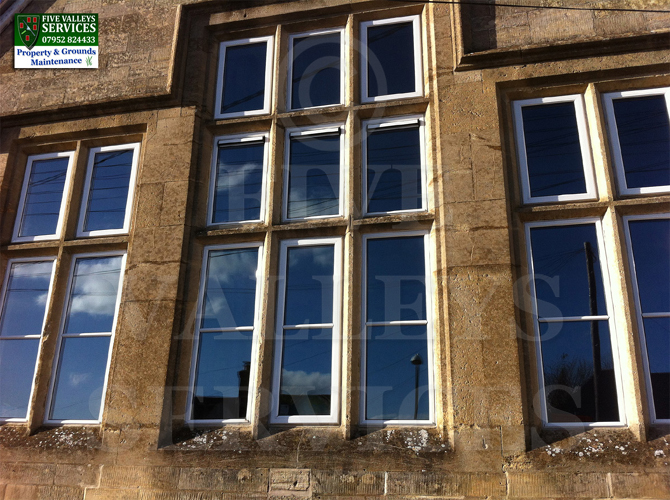 Tall multi-pane windows on a Cotswold stone building, cleaned
