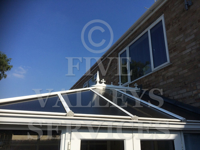 A conservatory roof and ridge against blue sky